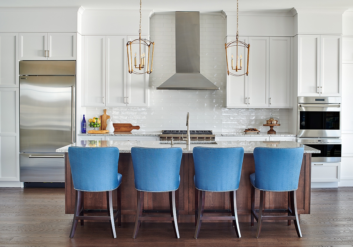 A white kitchen is enlivened by the contrasting blue kitchen barstools.